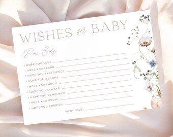 Può includere: Un biglietto per il baby shower bianco con la scritta "Wishes for Baby" e "Dear Baby". Il biglietto include suggerimenti per scrivere desideri ed è decorato con illustrazioni floreali in tonalità tenui. Il biglietto è su un tessuto color crema.