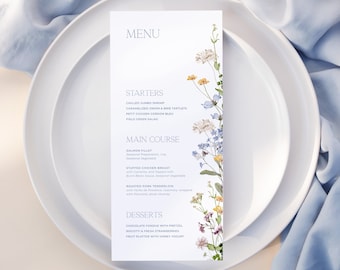 Könnte beinhalten: Eine Hochzeitskarte mit floralem Design. Das Menü umfasst Vorspeisen, Hauptgericht und Desserts. Der Text auf der Karte lautet: "MENU", "VORSPEISEN", "GEKÜHLTE RIESENGARNELEN", "KARAMELLISIERTES ZWIEBELN & BLAUE TÄRTCHEN", "KLEINES HÄHNCHEN CORDON BLEU", "FELDGRÜNER SALAT", "HAUPTGERICHT", "LACHSFILLET", "SAISONALES SPARGEL", "GEFÜLLTE HÄHNCHENBRUST", "GERÖSTETER SCHWEINEFILET", "DESSERTS", "SCHOKOLADENFONDUE MIT BREZEL", "BISCOTTI & FRISCHE ERDBEEREN", "FRUCHTPLATTE MIT HONIGJOGHURT", "LO BEHOLD".