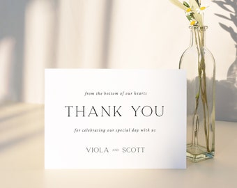 May include: A white thank you card with black text that reads "from the bottom of our hearts, THANK YOU, for celebrating our special day with us, VIOLA AND SCOTT, LO BEHOLD".