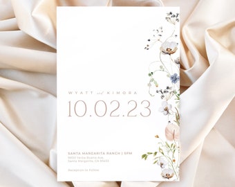 May include: A wedding invitation with a floral design in shades of blue, white, and pink. The text reads "WYATT and KIMORA 10.02.23 SANTA MARGARITA RANCH | SPM 9000 Yerba Buena Ave, Santa Margarita, CA 93451 Reception to Follow LO BEHOLD".