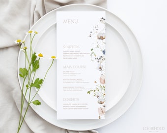 Op de afbeelding: Een witte menukaart met een bloemenontwerp aan de rechterkant. Het menu is getiteld "MENU" en vermeldt de voorgerechten, het hoofdgerecht en de desserts. De voorgerechten omvatten gekoelde jumbo garnalen, gekarameliseerde ui & brie taartjes, petit chicken cordon bleu en veldsla. Het hoofdgerecht omvat zalmfilet, gevulde kipfilet en geroosterde varkenshaas. De desserts omvatten chocolade fondue met pretzels, biscotti & verse aardbeien en een fruitplateau met honingyoghurt.