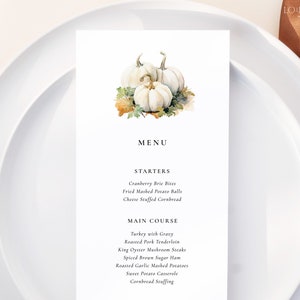 May include: A Thanksgiving menu with a watercolor illustration of white pumpkins. The menu includes starters such as cranberry brie bites, fried mashed potato balls, and cheese stuffed cornbread. The main course includes turkey with gravy, roasted pork tenderloin, king oyster mushroom steaks, spiced brown sugar ham, roasted garlic mashed potatoes, sweet potato casserole, and cornbread stuffing.