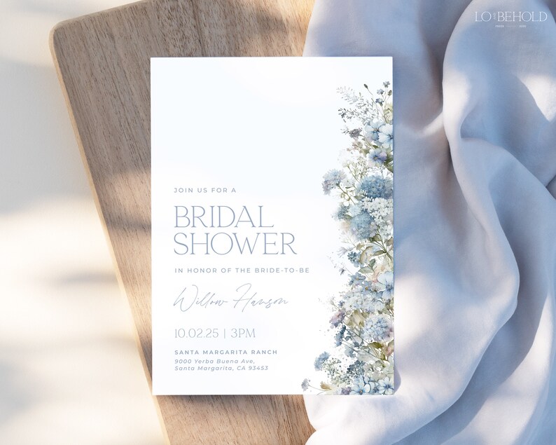 May include: A white bridal shower invitation with blue watercolor flowers on the right side. The text reads "Join us for a Bridal Shower in honor of the bride-to-be Willow Herson 10.02.25 | 3PM Santa Margarita Ranch 9000 Yerba Buena Ave, Santa Margarita, CA 93453"