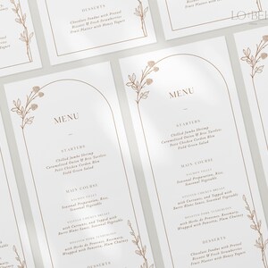 May include: A white menu card with a brown floral design and a gold arch. The menu includes starters, main course, and desserts. The menu items are listed in a simple, elegant font.