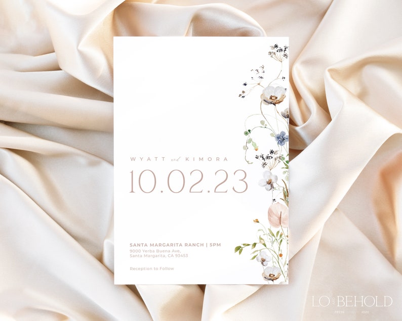 May include: A white wedding invitation with a floral design in shades of blue, pink, and green. The text reads "WYATT and KIMORA 10.02.23 SANTA MARGARITA RANCH | SPM 9000 Yerba Buena Ave, Santa Margarita, CA 93453 Reception to Follow LO BEHOLD"