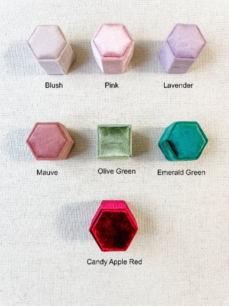 May include: Assortment of hexagon-shaped velvet ring boxes in various colors, including blush, pink, lavender, mauve, olive green, emerald green, and candy apple red.