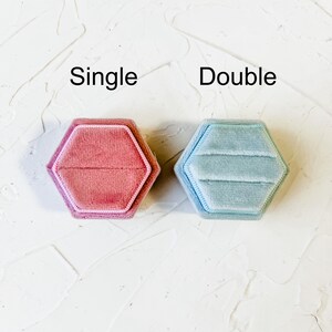 May include: Two velvet ring boxes, one pink and one light blue, with the words "Single" and "Double" printed above them.