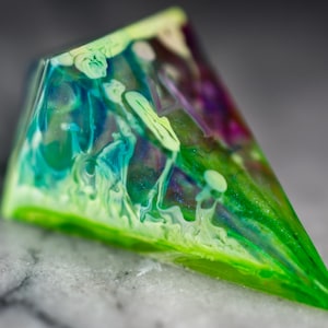 May include: A triangular, clear resin paperweight with swirls of green, blue, and purple.