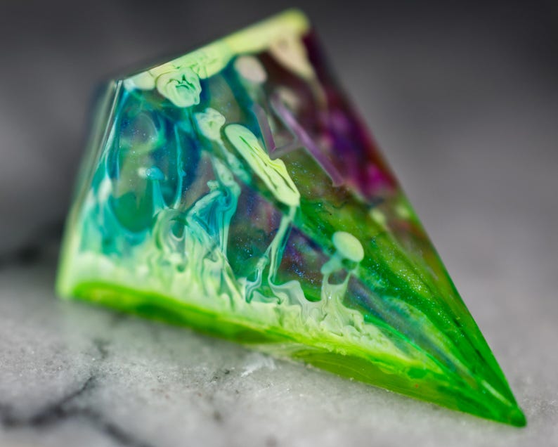 May include: A triangular, clear resin paperweight with swirls of green, blue, and purple.
