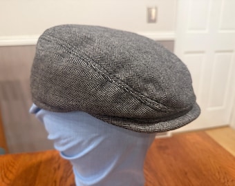May include: A gray and black herringbone patterned newsboy cap.