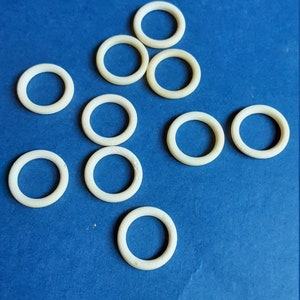 May include: Ten white plastic rings on a blue background. The rings are all the same size and shape.