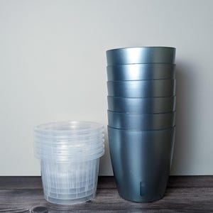 a stack of 6 metallic teal self watering pots. Metallic teal outer pot and clear inner pot sit next to each other.