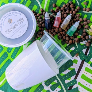 May include: A starter kit for hydroponic gardening with a white plastic container, a white plastic pot, and four small bottles of liquid plant food. The kit also includes a bag of clay pebbles. The container has the text "Starter Kit" and "LECA ADDICT" printed on it.