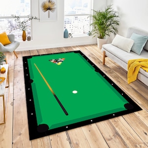 May include: A green felt pool table rug with black edging and a white cue ball. The rug features a brown pool cue and a triangle of colourful billiard balls.