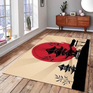 May include: A beige rug with a red sun and black silhouette of a Japanese pagoda and trees. The rug has a graphic design with a sunburst pattern.