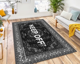 May include: Black and gray area rug with a white "KEEP OFF" text in a stylized font. The rug has a traditional paisley pattern border.