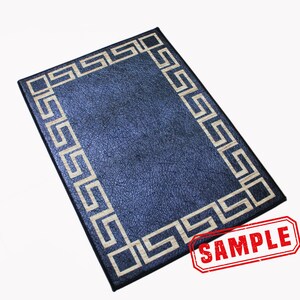 Puede incluir: Una alfombra rectangular de color azul oscuro con un borde blanco en forma de llave griega. La alfombra tiene una superficie texturizada y la palabra "SAMPLE" est&aacute; estampada en rojo en la esquina inferior derecha.
