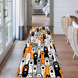 May include: A long, narrow rug with a repeating pattern of colorful cat paws. The paws are orange, gray, black, and white. The rug is perfect for adding a playful touch to any hallway or entryway.