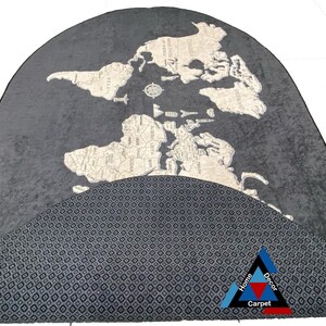 May include: A gray and white world map rug with a black and white geometric pattern on the bottom half. The rug is in the shape of a half circle. The text "Home Decor Carpet" is in the bottom right corner.