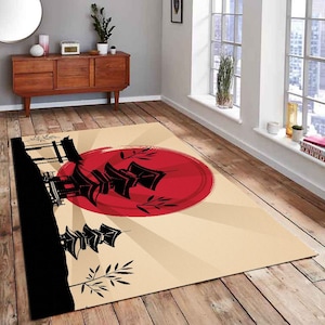 May include: A beige rug with a black silhouette of a Japanese pagoda and a red sun rising behind it. The rug has a stylized design with black bamboo shoots and a white background.