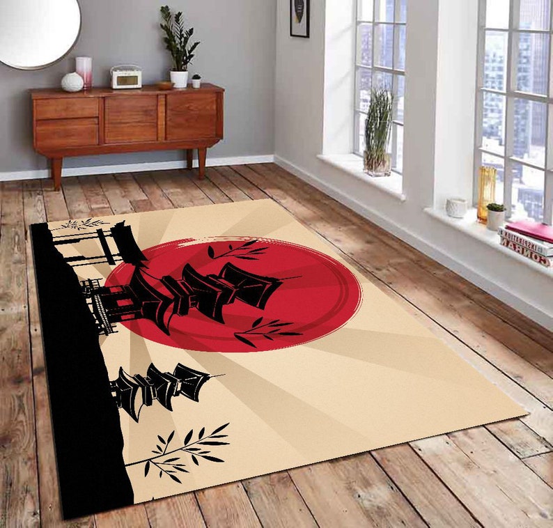 May include: A beige rug with a black silhouette of a Japanese pagoda and a red sun rising behind it. The rug has a stylized design with black bamboo shoots and a white background.