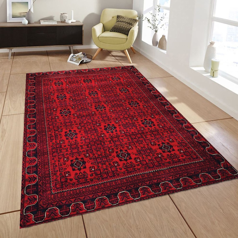 May include: A red rug with a black and white geometric pattern. The rug has a border with a repeating design.