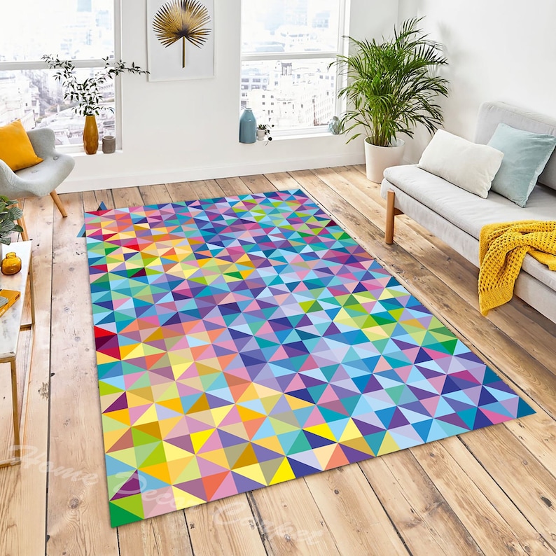 May include: A colourful geometric rug with a pattern of small triangles in shades of blue, green, yellow, pink, and purple. The rug is laid out on a wooden floor in a living room setting.