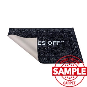 K&ouml;nnte beinhalten: Schwarz-wei&szlig;er Teppich mit Muster und dem Text "Off" in Wei&szlig;. Der Teppich ist zur H&auml;lfte gefaltet und hat eine wei&szlig;e R&uuml;ckseite. Der Teppich hat ein Etikett mit der Aufschrift "Home Decor Sample Carpet".