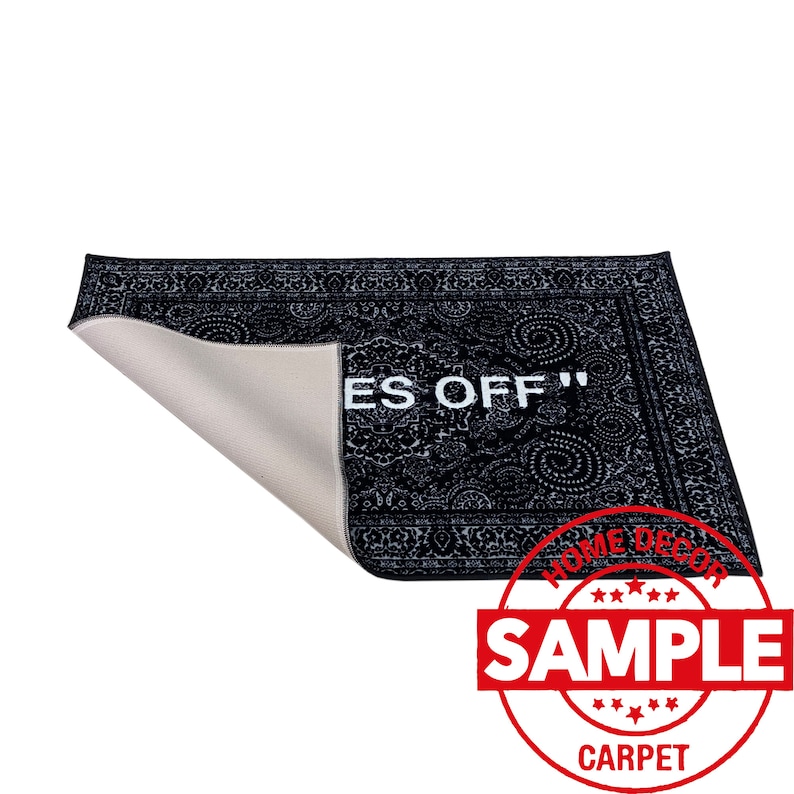 K&ouml;nnte beinhalten: Schwarz-wei&szlig;er Teppich mit Muster und dem Text "Off" in Wei&szlig;. Der Teppich ist zur H&auml;lfte gefaltet und hat eine wei&szlig;e R&uuml;ckseite. Der Teppich hat ein Etikett mit der Aufschrift "Home Decor Sample Carpet".