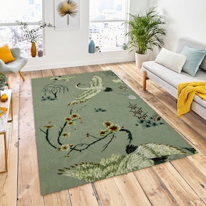 May include: A green rug with a floral and crane design. The rug features a light green background with white cranes, green leaves, and pink flowers.