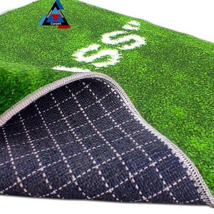 May include: A green and white artificial grass rug with the word "GO" printed in white. The rug has a black and white checkered backing.