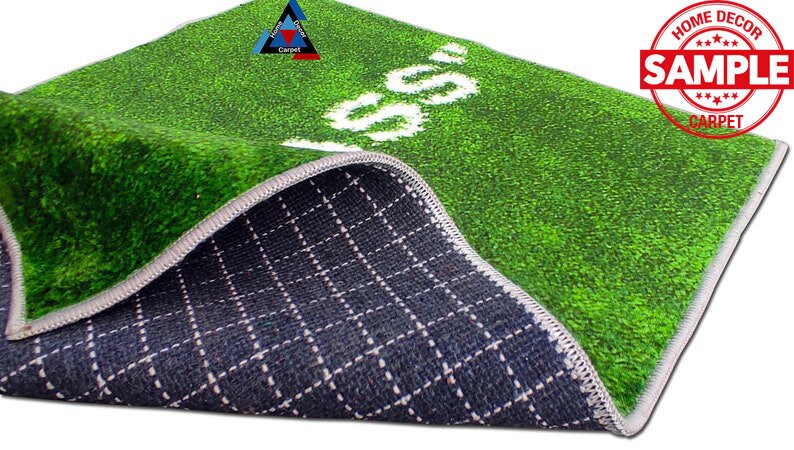 May include: A green and white artificial grass rug with the word "GO" printed in white. The rug has a black and white checkered backing.