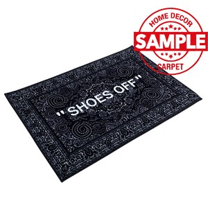 K&ouml;nnte beinhalten: Schwarz-wei&szlig;er Fu&szlig;abtreter mit Paisley-Muster und dem Text "Shoes Off" in Wei&szlig;.