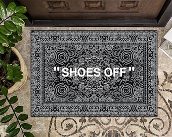 May include: Black and white doormat with a paisley pattern and the text "SHOES OFF" in white.