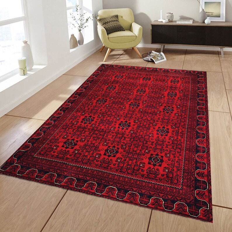 May include: A red rug with a black and white geometric pattern. The rug has a detailed border with a repeating design.