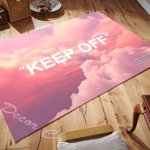 Può includere: Tappeto rosa e bianco con un design a nuvole e il testo "KEEP OFF" stampato in bianco. Il tappeto presenta un sottile effetto sfumato, passando da un rosa più scuro a un rosa più chiaro.