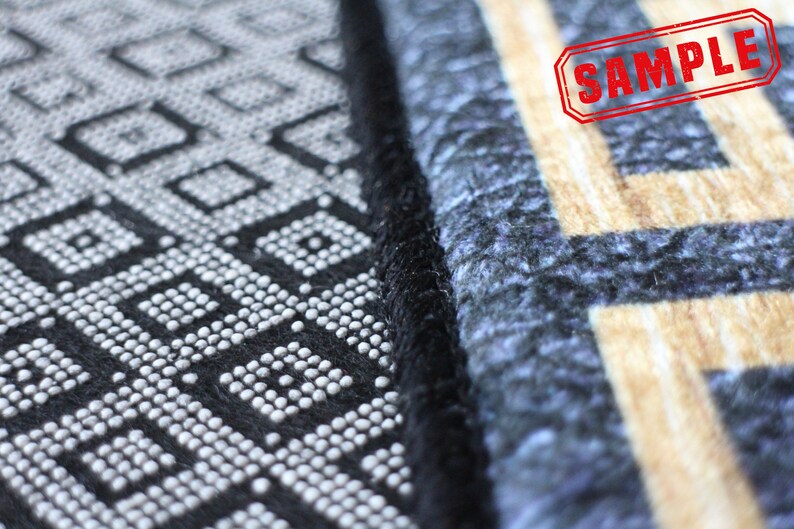 Puede incluir: Primer plano de una alfombra de patr&oacute;n blanco y negro con un borde negro. La alfombra tiene un dise&ntilde;o geom&eacute;trico con peque&ntilde;os c&iacute;rculos blancos. La alfombra est&aacute; junto a una alfombra de patr&oacute;n azul y beige con un borde negro. La palabra "SAMPLE" est&aacute; estampada en rojo en la alfombra beige.
