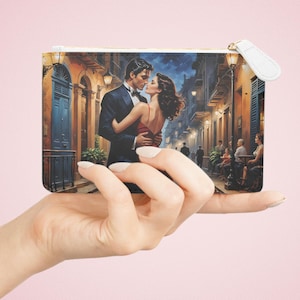 May include: A white zippered pouch with a colorful image of a couple dancing in a city street. The couple is dressed in formal attire and the man is wearing a dark suit and the woman is wearing a red dress.