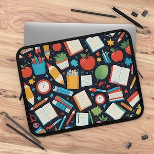 以下が含まれることがあります： カラフルな鉛筆、本、リンゴ、時計などの学用品が描かれた黒いノートパソコン用スリーブ。パターンはスリーブ全体に繰り返されています。
