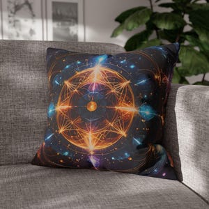 May include: A decorative throw pillow with a geometric design featuring a glowing orange and yellow mandala surrounded by a dark blue background with scattered stars and light blue accents.