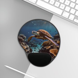May include: A round mouse mat with a black wrist rest. The mat features a colourful underwater scene with a sea turtle swimming through coral reefs.
