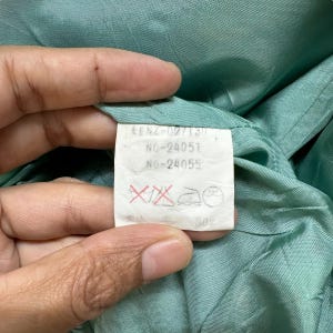 May include: A white tag with black text and red markings. The tag reads "EENZ-027130", "NO-24051", "NO-24055", and "80%".
