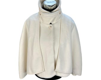 May include: A white fleece cape with a high collar and a single button closure. The cape has a relaxed fit and is perfect for layering.