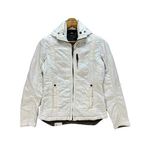 May include: Off-white quilted jacket with a high collar and a full-length zipper. The jacket features a quilted pattern, two front pockets, and the G-Star Raw logo on the upper right chest. The jacket is designed for cold weather.