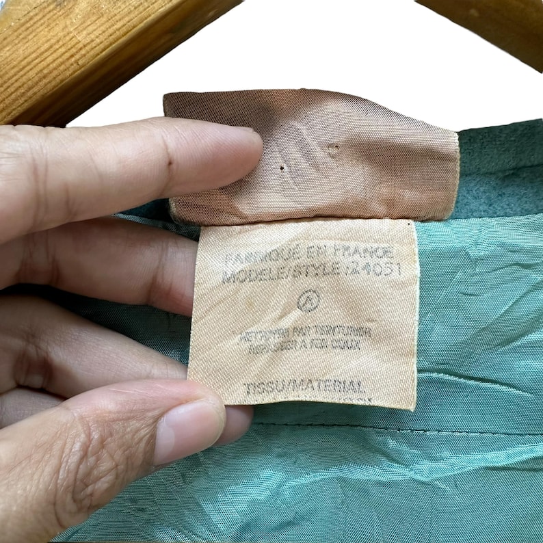 May include: A close-up of a light blue fabric label with the text "Fabrique en France, Modele/Style: 24051" and "Tissu/Material" printed on it.