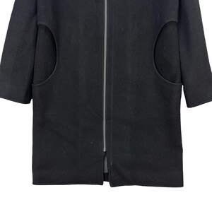 Peut inclure: Un manteau noir avec une fermeture &eacute;clair sur toute la longueur et des manches courtes. Le manteau comporte deux grandes poches arrondies sur le devant. Le manteau est fait d'un tissu &eacute;pais et fonc&eacute;.