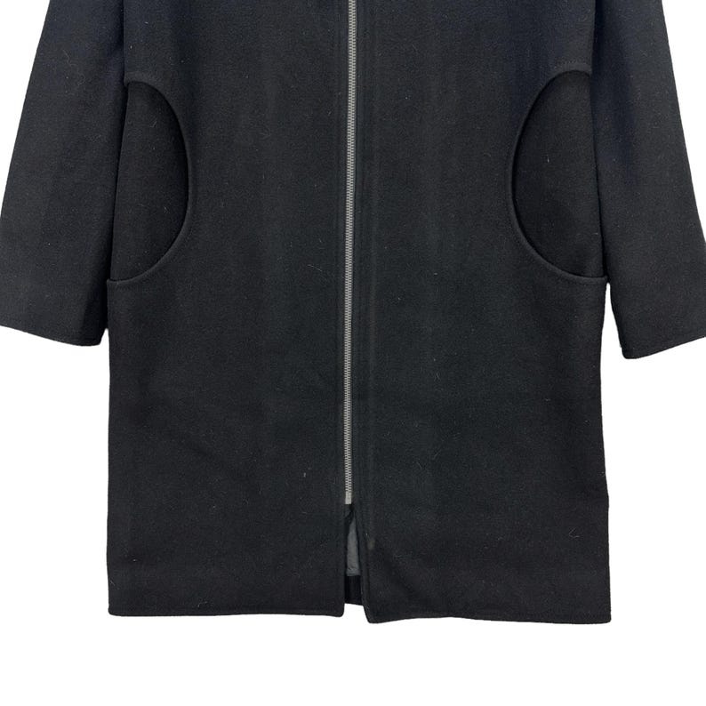 Peut inclure: Un manteau noir avec une fermeture &eacute;clair sur toute la longueur et des manches courtes. Le manteau comporte deux grandes poches arrondies sur le devant. Le manteau est fait d'un tissu &eacute;pais et fonc&eacute;.