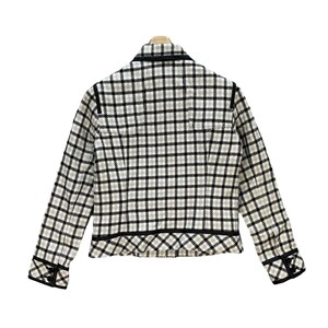 May include: A white and black checked blazer with a black trim around the collar, cuffs, and hem. The blazer has a fitted silhouette and a button closure.