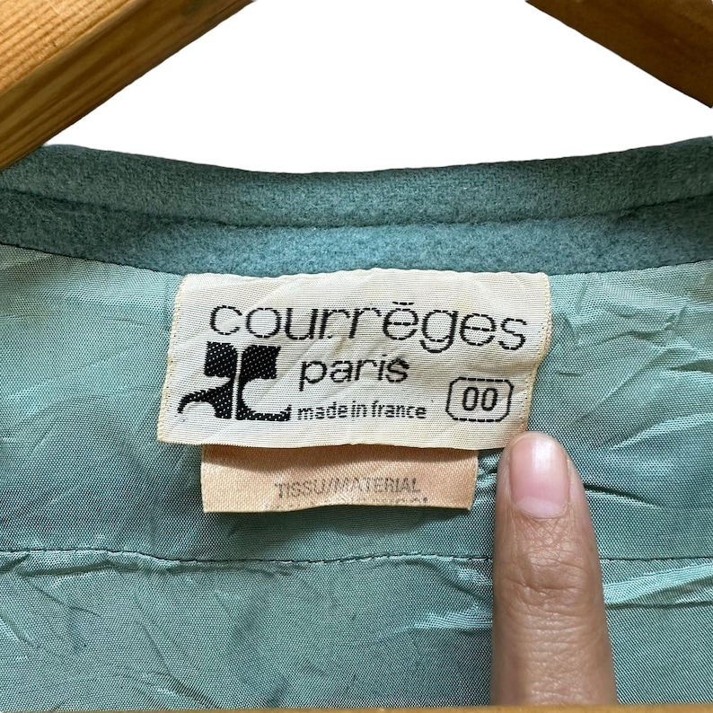 May include: A light blue label with the text "Courr&egrave;ges Paris made in France 00" in black. The label is attached to a light blue fabric.