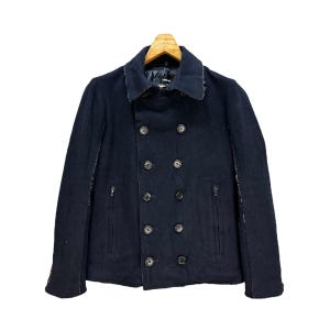 May include: A dark blue peacoat with a double-breasted closure and six buttons. The coat has a collar that can be folded up or down, and two pockets on the front. The coat is made of a thick, warm fabric.